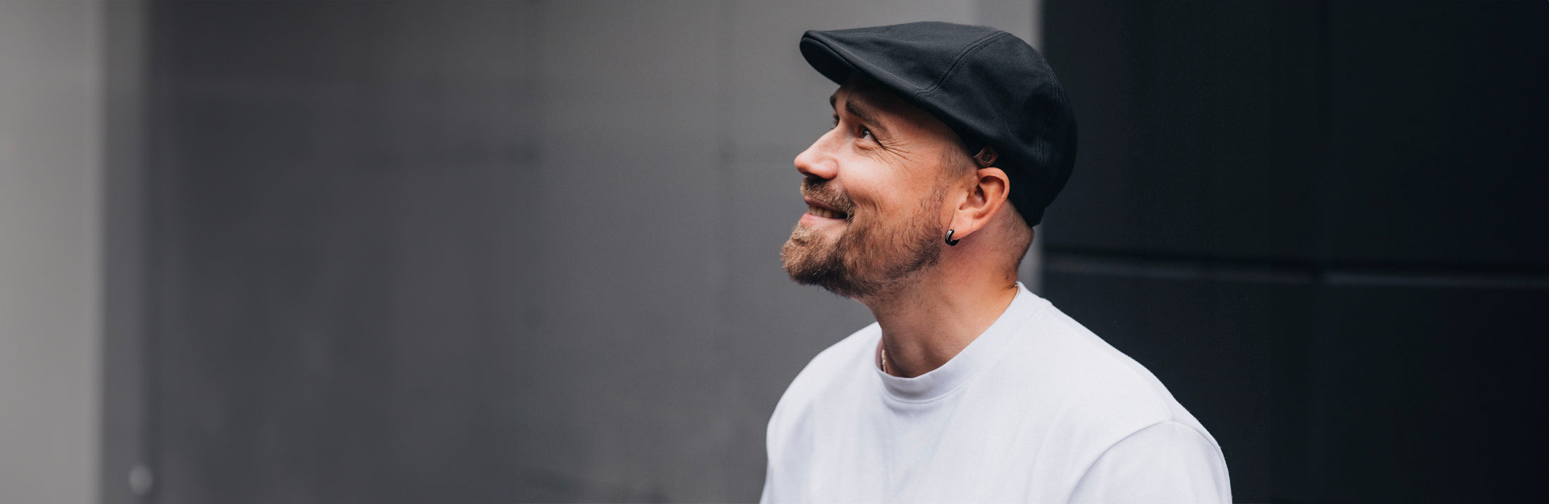 iloinen mies päällään valkoinen t-paita ja päässä musta lakki