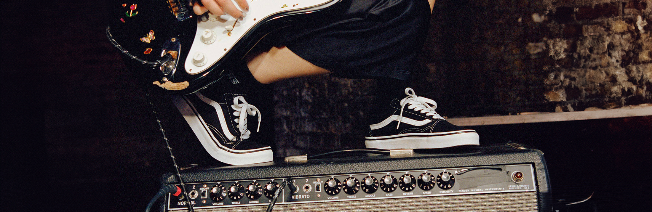 mies seisoo mustat vans tennarit jalassa vahvistimen päällä